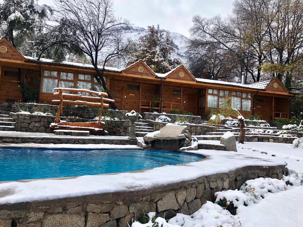 a log cabin with a swimming pool in the snow at Refugio del Maipo Lodge in San José de Maipo