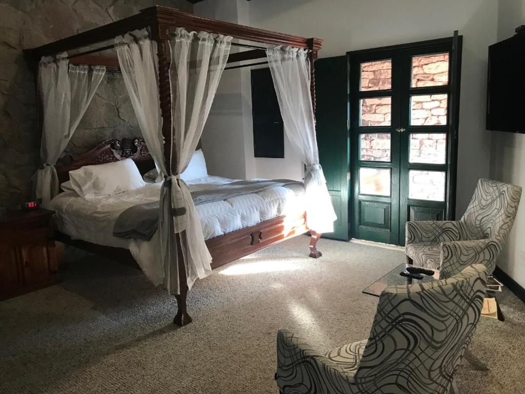 1 dormitorio con cama con dosel y silla en Hotel Canaria en Santeagueda