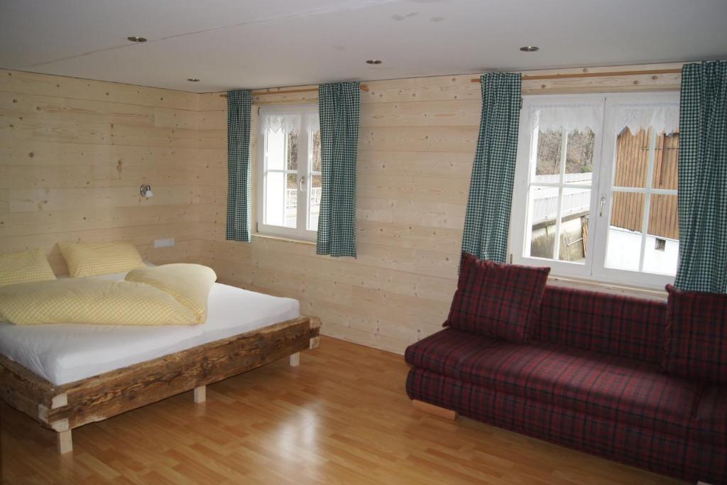 Cette chambre comprend un lit, un canapé et des fenêtres. dans l'établissement Ferienhaus Schindeler, à Mellau