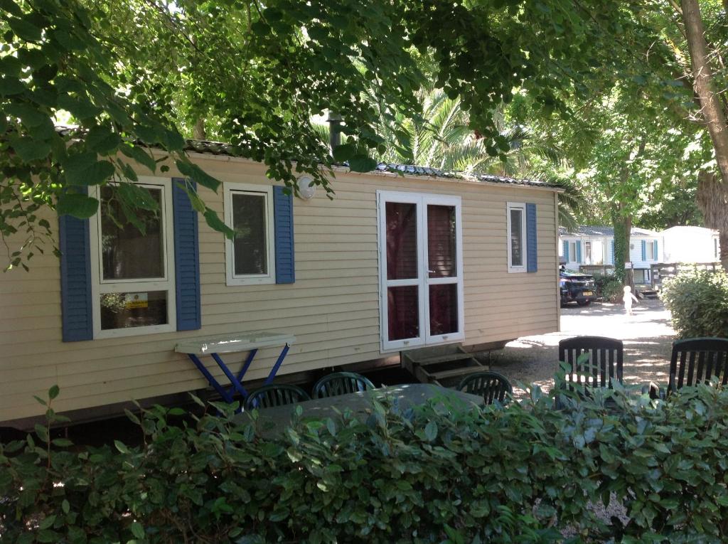 une petite maison jaune avec des chaises et une table dans l'établissement TopSun Argelès Camping La Sirène 2 bedroom 25m2 max 4 personnes Inc bebe pas d'enfants sans parents, à Argelès-sur-Mer