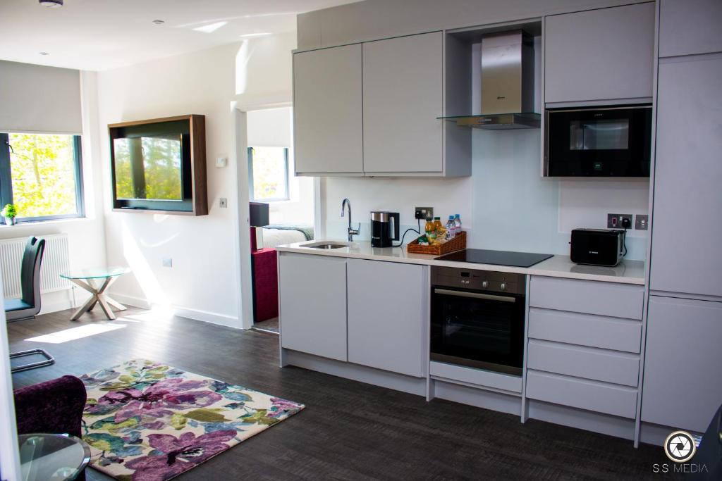 a kitchen with white cabinets and a kitchen rug at LuxuStay Serviced Apartments in Milton Keynes