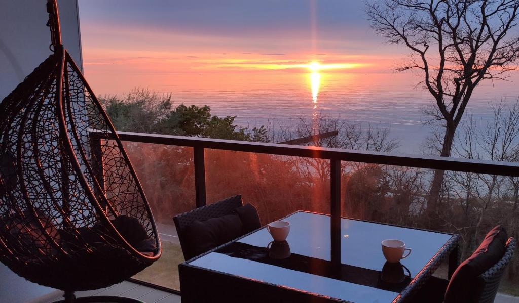 uma varanda com mesa e cadeiras e um pôr-do-sol em Sea View Moss VIP Apartment em Kolobrzeg