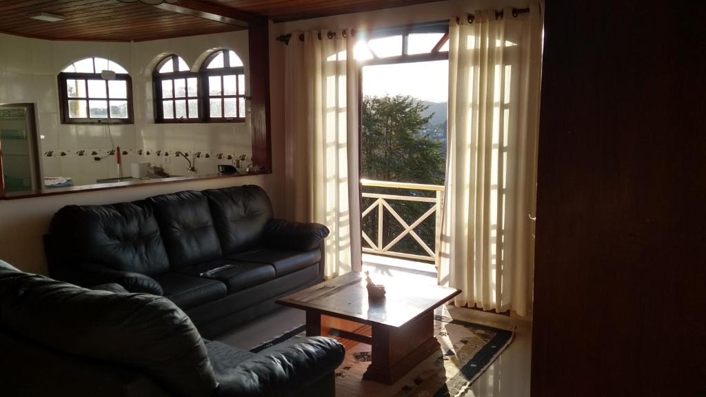ein Wohnzimmer mit einem Sofa, einem Tisch und einem Fenster in der Unterkunft Apartamento Campos do Jordão in Campos do Jordão