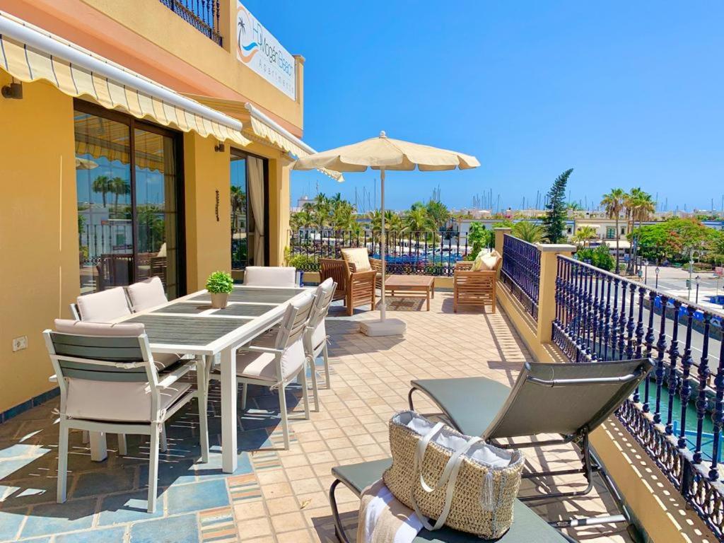 een patio met een tafel en stoelen en een parasol bij HD Mogan Beach Apartment in Puerto de Mogán