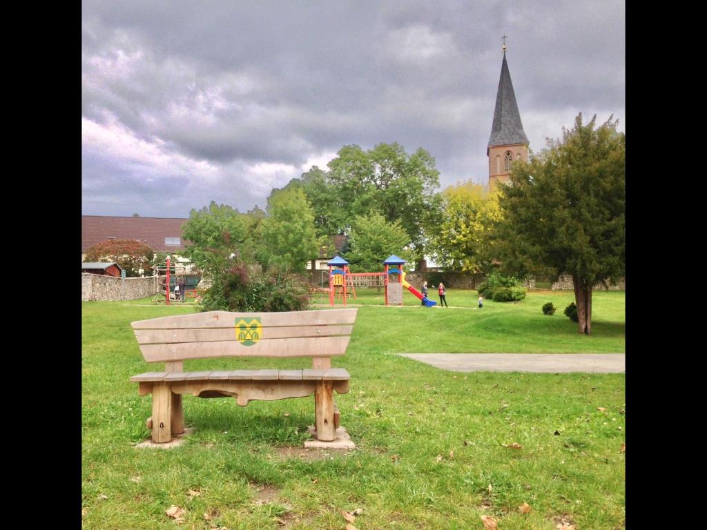 a wooden bench in a park with a playground at Ferienhaus Live Deluxe in der schönen Uckermark in Meyenburg