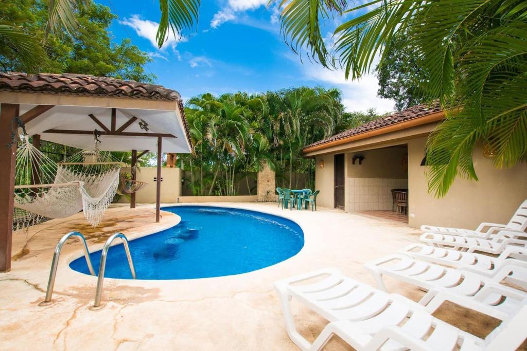 uma piscina com cadeiras e uma rede ao lado de uma casa em Nicely priced well-decorated unit with pool near beach in Brasilito em Brasilito