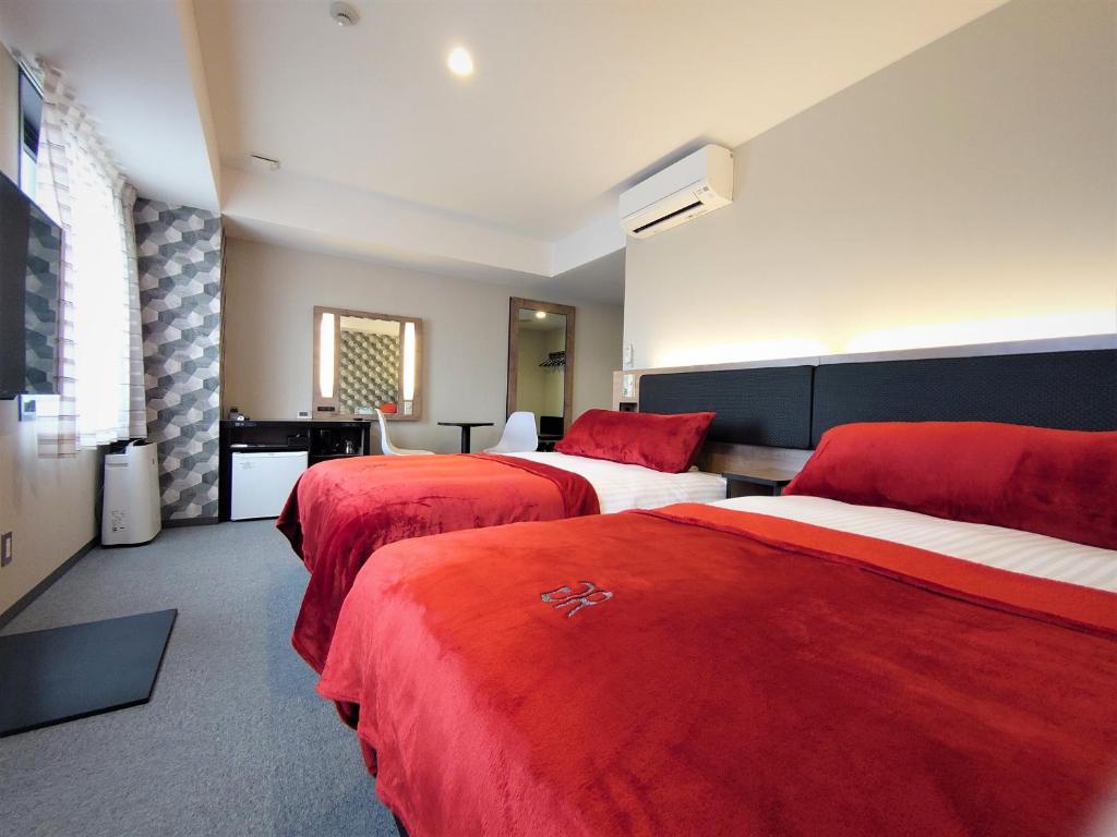 a hotel room with two beds with red covers at Green Rich Hotel Yonago Ekimae (Artificial hot spring Futamata Yunohana) in Yonago