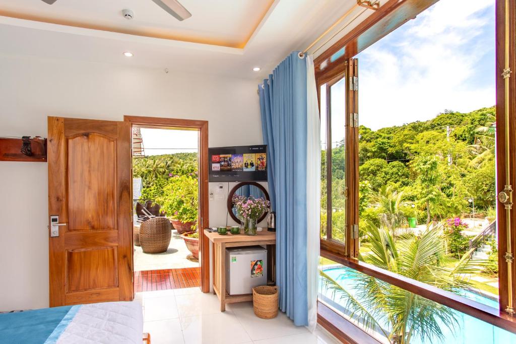 a bedroom with a large window with a view of the garden at Caesar Phu Quoc Hotel in Phú Quốc