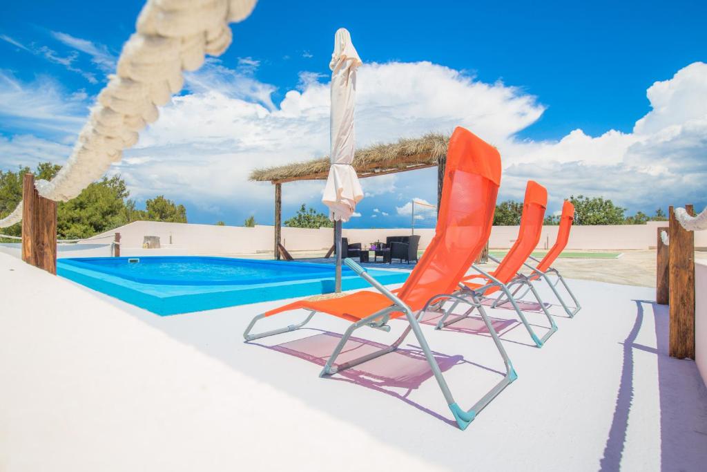 - deux chaises, un parasol et une piscine dans l'établissement Holiday House El Dorado!!, à Primošten
