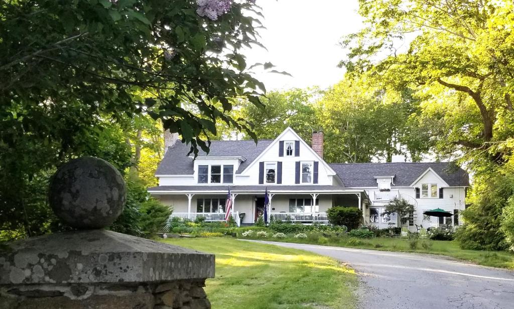 uma casa branca com uma estátua em frente em Timbercliffe Cottage Inn em Camden