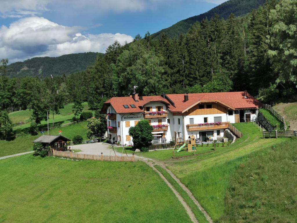 ein großes Haus mitten auf einem grünen Feld in der Unterkunft Rauchenbichlerhof in Bruneck