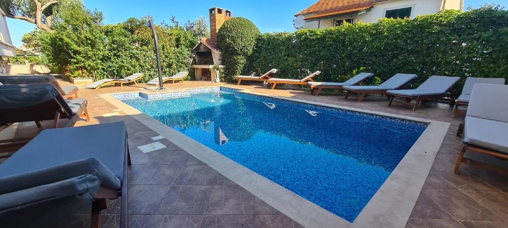 a swimming pool with blue water in a yard at Apartments Mery in Supetar