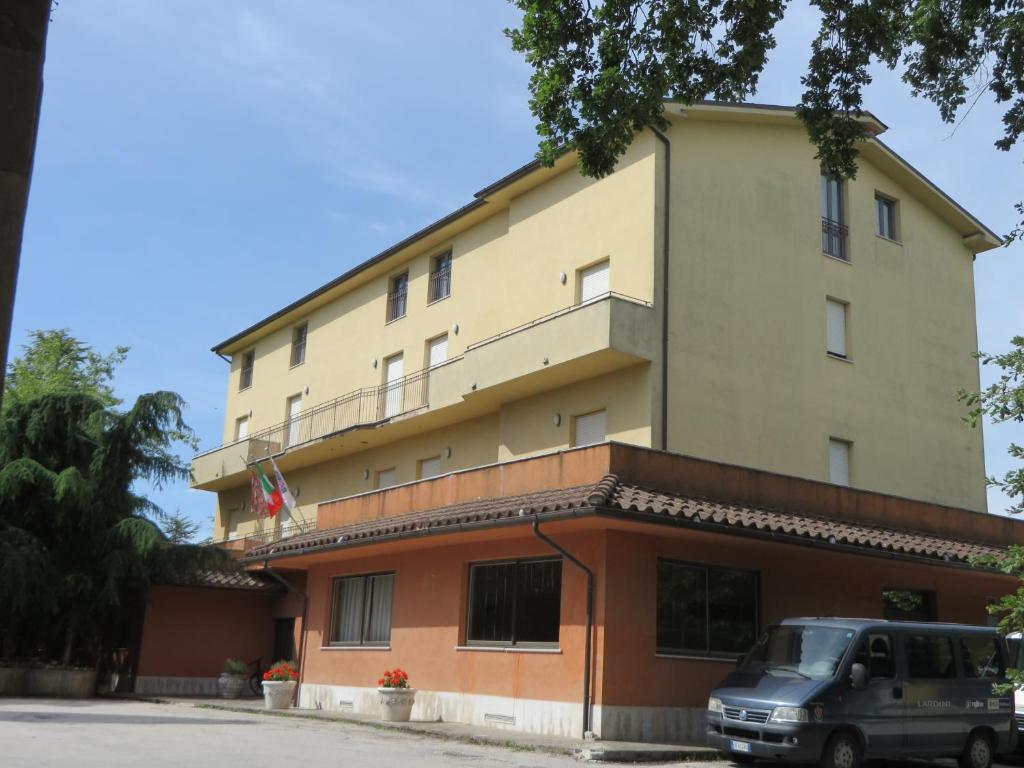 Filottrano的住宿－Hotel Ostello Settecolli Sport，前面有停车位的建筑