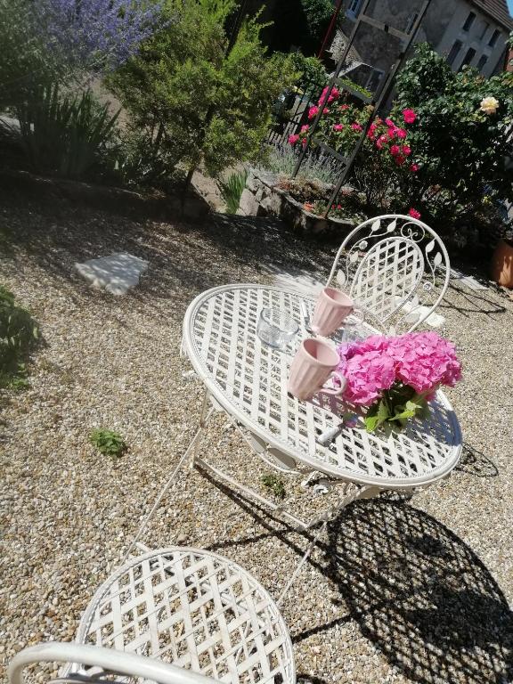 une table blanche avec des fleurs roses en haut dans l'établissement Gîte Pierre et Marie, à Mellecey