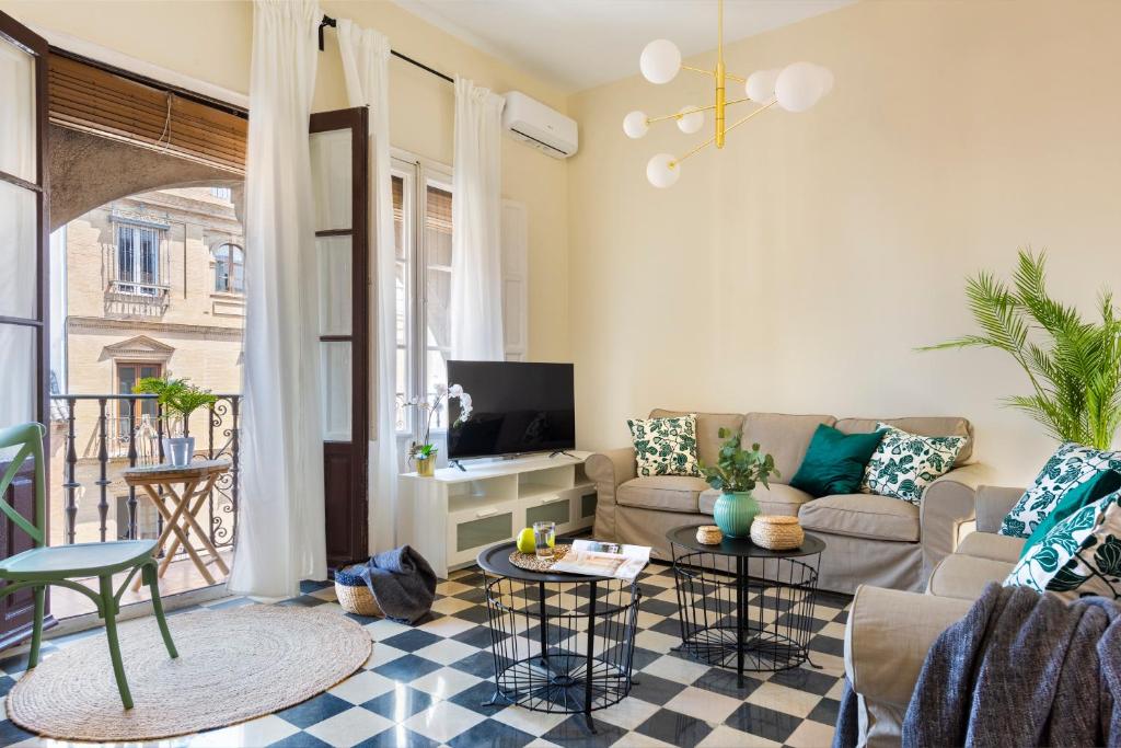 uma sala de estar com um sofá e uma televisão em HSH Suites Campana em Sevilha