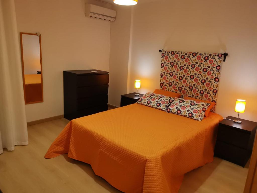 een slaapkamer met een oranje bed en 2 lampen bij Isis & Isa in Monte Gordo