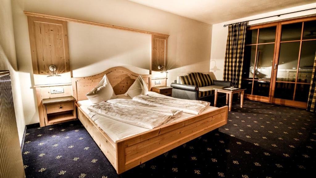 een slaapkamer met een groot houten bed en een stoel bij Hotel Vermoi in Laces