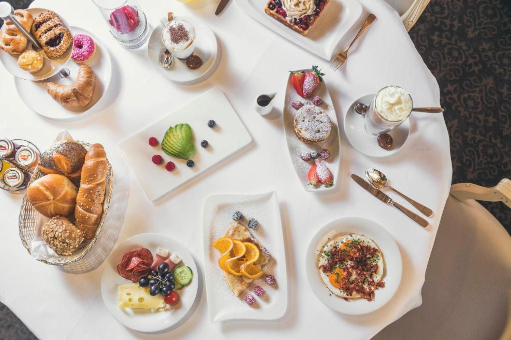 a white table topped with plates of food and desserts at Schlosshotel Ischgl 5-Sterne Superior in Ischgl