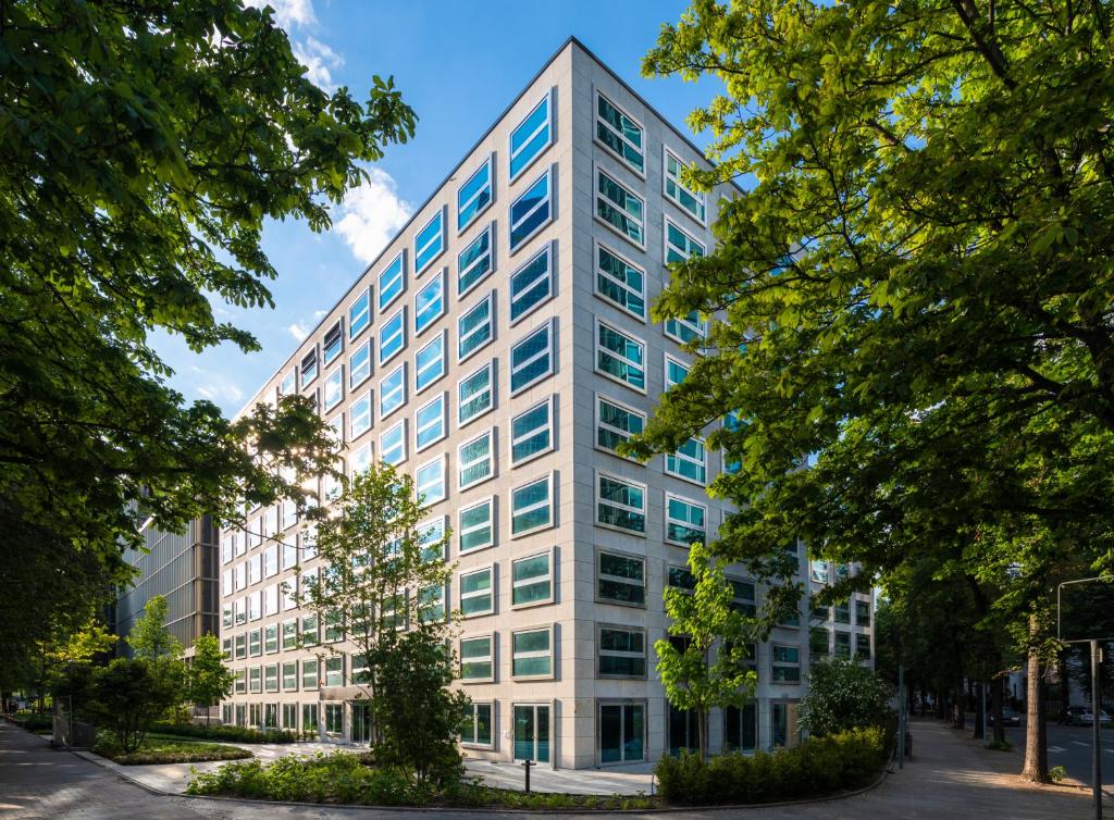 ein weißes Bürogebäude mit Bäumen davor in der Unterkunft THE FLAG West M. in Frankfurt am Main