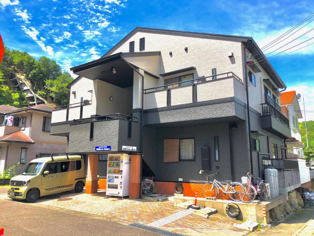 uma casa com um carro estacionado em frente em Midtown Sakura Apartment House 101 予約者だけの空間 A space just for you em Nachikatsuura