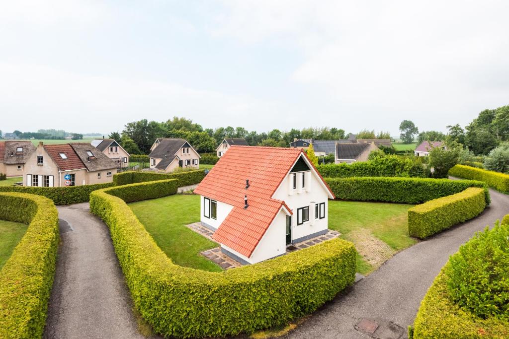 ein kleines weißes Haus mit orangefarbenem Dach im Garten in der Unterkunft Vacation Home 23 in Tzummarum