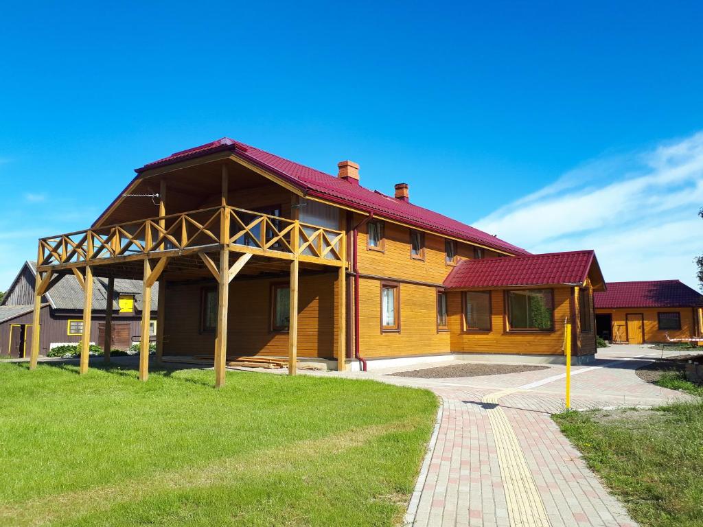 een groot houten huis met een rood dak bij Dvēseles veldzes dārzs in Ziemupe