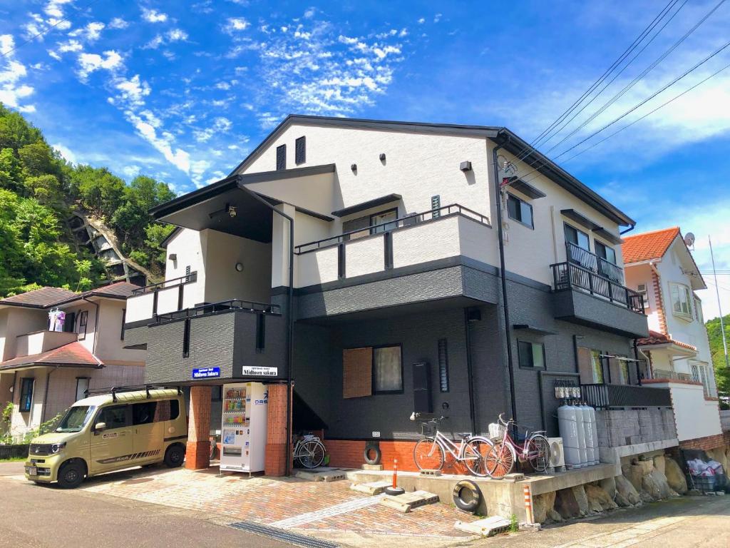 ein Haus, das mit einem Van vor dem Haus gebaut wird in der Unterkunft Midtown Sakura Apartment House 102 予約者だけの空間 A space just for you in Katsuura