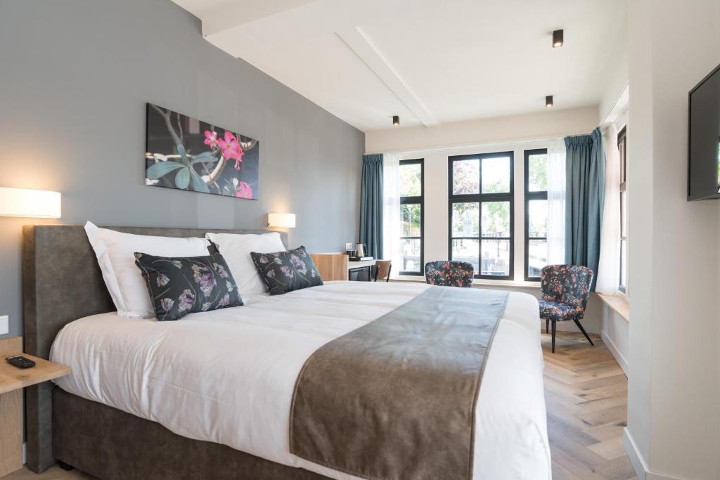 a bedroom with a large bed and two chairs at Hof van Holland Hotel in Edam