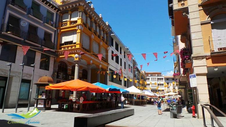 una calle de la ciudad con sombrillas y edificios con gente caminando en Hotel Clemente en Barbastro