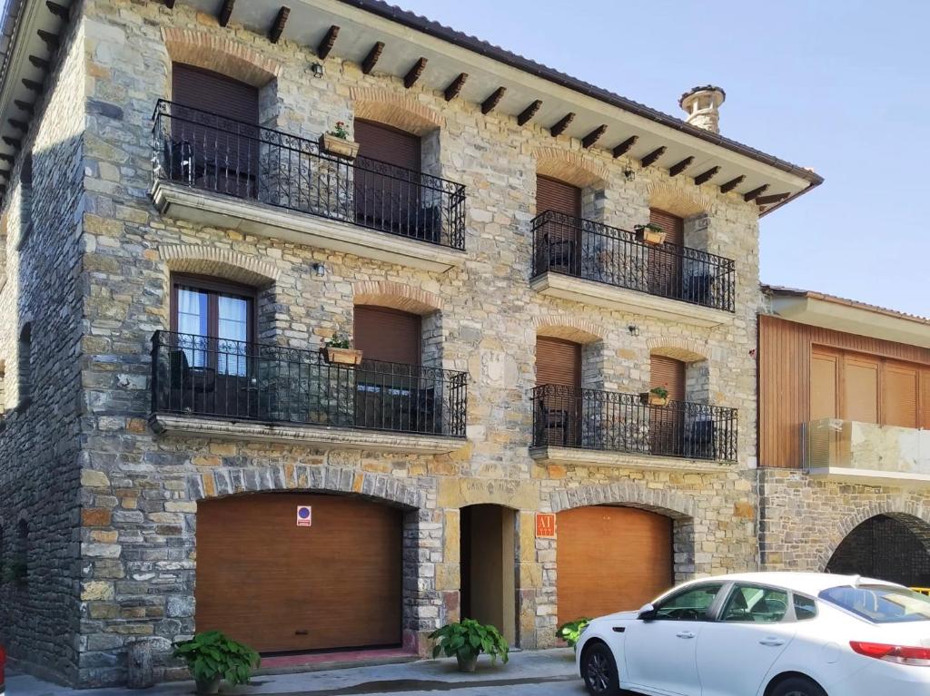 een witte auto geparkeerd voor een stenen gebouw bij Apartamentos Turismo Rural Casa Alfós in Labuerda