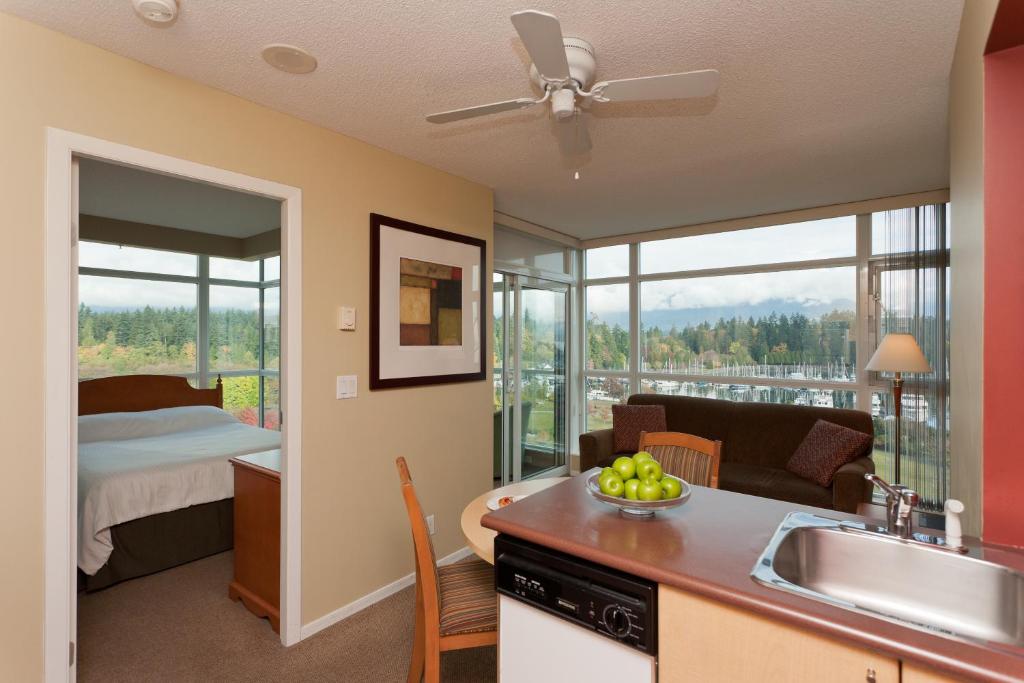 a kitchen and living room with a view of a bedroom at Lord Stanley Suites On The Park in Vancouver