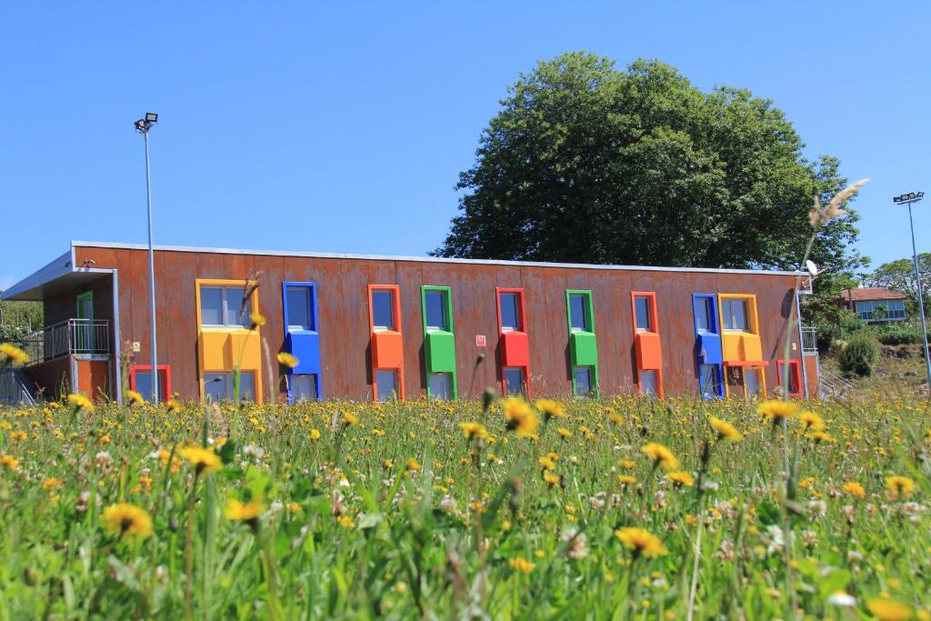 a building with colorful doors in a field of flowers at CELTAINER in Maceda