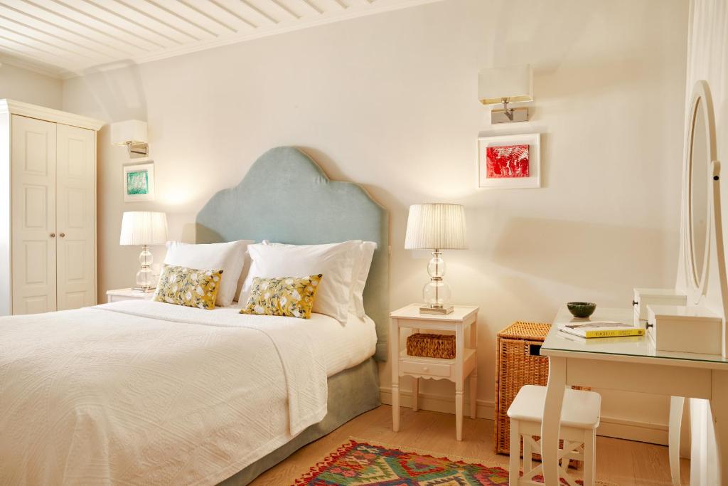 ein weißes Schlafzimmer mit einem Bett und einem Schreibtisch in der Unterkunft Old Town Luxury Suites 'Komissa' in Korfu-Stadt