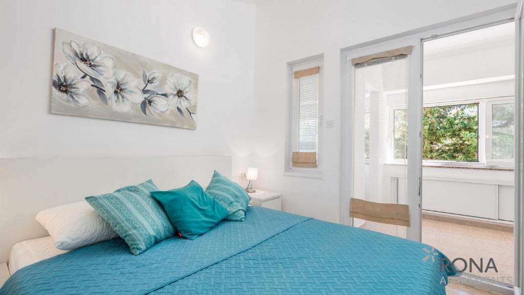 sypialnia z niebieskim łóżkiem i oknem w obiekcie Rona Apartment Flower 1 and Flower 2 w Novalji