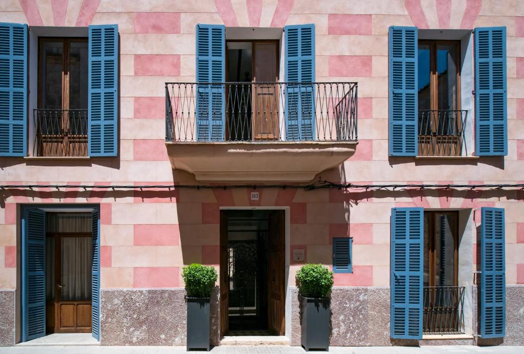 a pink building with blue shutters and windows at Es Picarol Sineu in Sineu