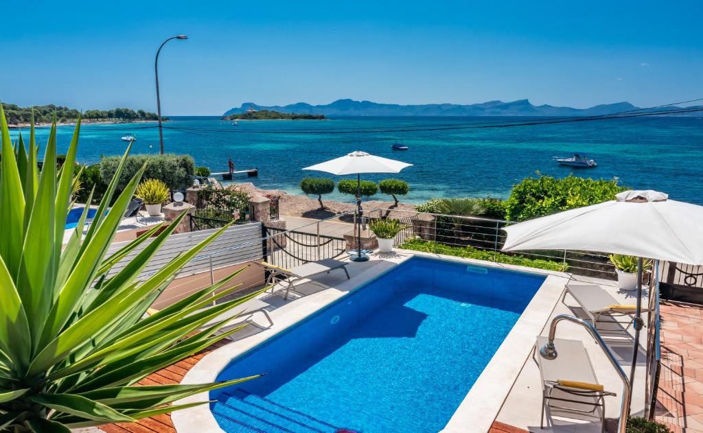 a swimming pool with a view of the ocean at Villa FARO Alcanada - Alcudia in Alcudia
