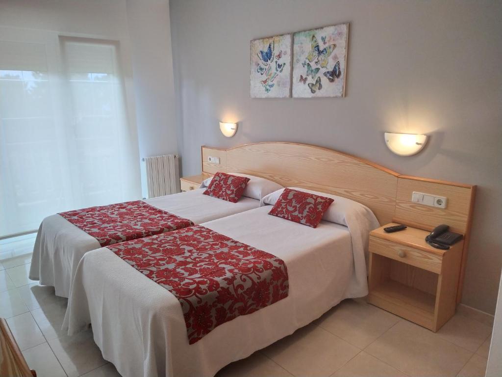 a bedroom with a large bed with a red blanket at Pension Playa Mar Cachadiñas in Balea