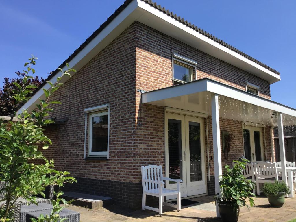 a brick house with two white chairs in front of it at Het Groene Hart in Putten