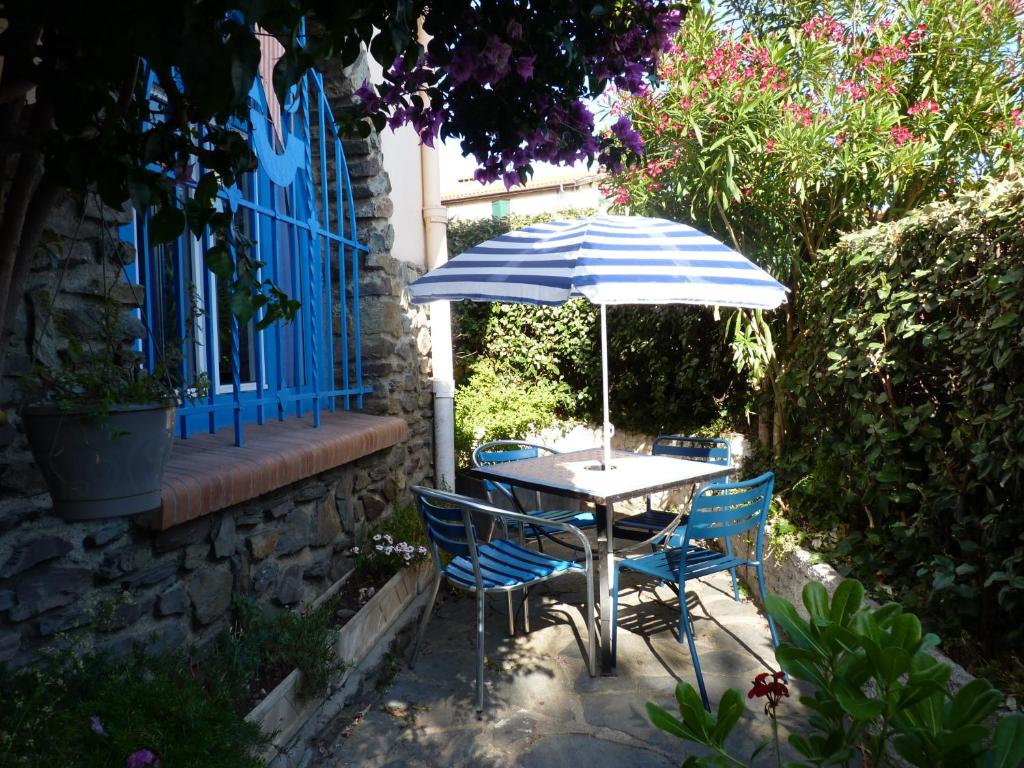 - une table et des chaises avec un parasol dans le jardin dans l'établissement La grande bleue, à Banyuls-sur-Mer
