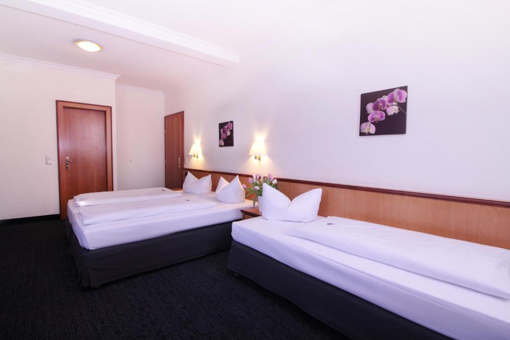 2 Betten in einem Hotelzimmer mit weißen Wänden in der Unterkunft Landhotel Hirsch in Kempten