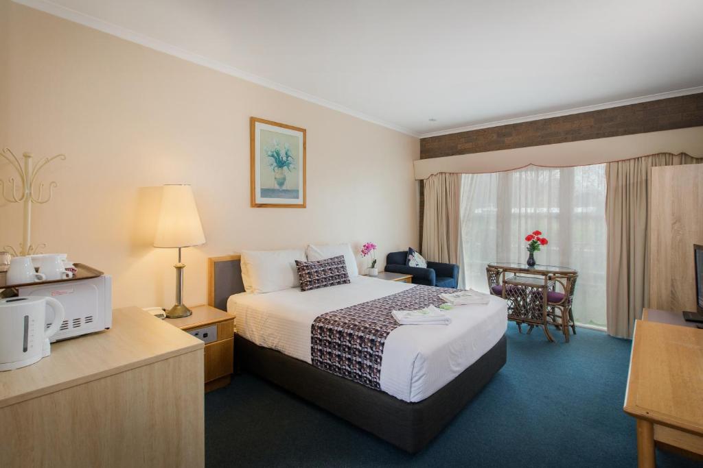 a hotel room with a large bed and a table at Australia Park Motel in Albury