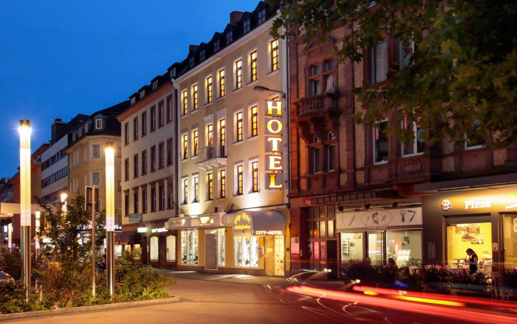 a city street at night with buildings and a car at City-Hotel Aschaffenburg in Aschaffenburg