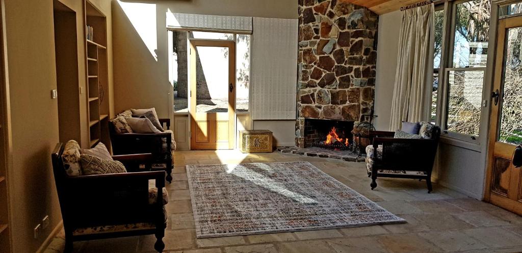 a living room with a fireplace and a stone wall at Olinda Yarra Cottage in Yering