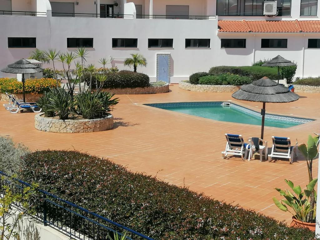 a swimming pool with chairs and umbrellas next to a building at Casa Sílvia in Lagos