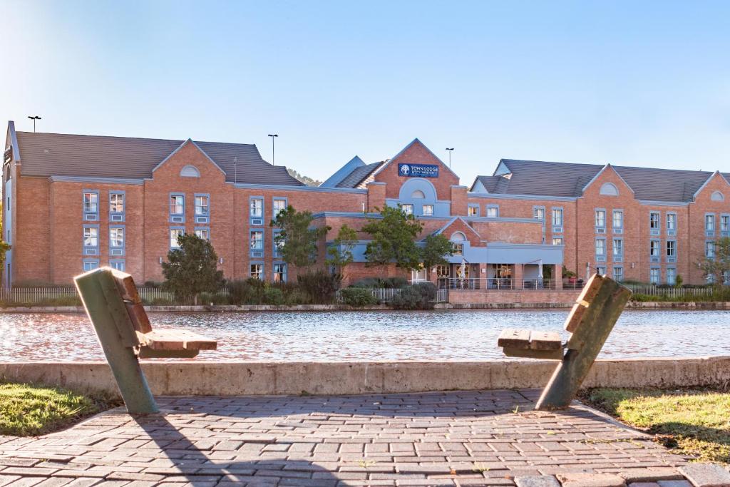 two benches sitting in front of a large building at Town Lodge Roodepoort in Roodepoort