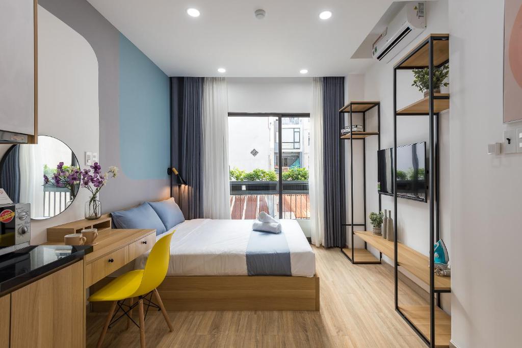 a bedroom with a bed and a desk with a yellow chair at Cozrum Homes Ambera House in Ho Chi Minh City
