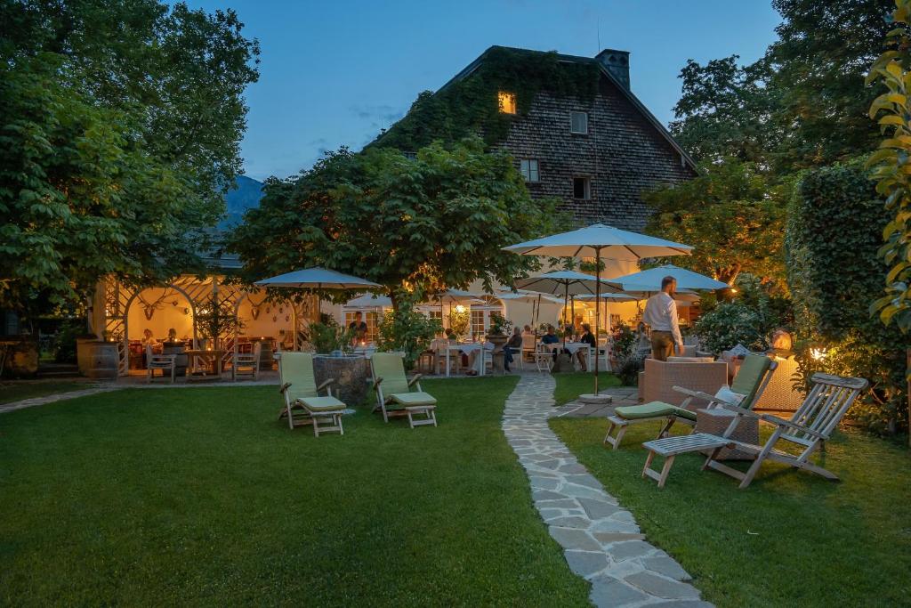 a backyard with chairs and tables and umbrellas at night at Der Schlosswirt zu Anif - Biedermeierhotel und Restaurant in Anif