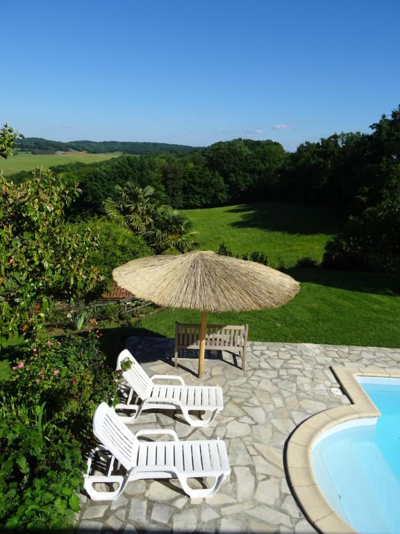 un grupo de sillas y una sombrilla junto a una piscina en Au Moulié, en Blousson-Sérian