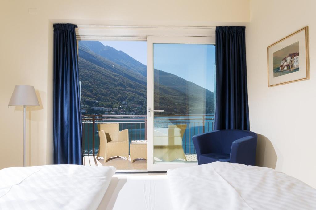 a bedroom with a bed and a chair and a window at Hotel Maximilian in Malcesine