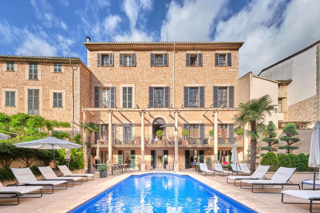 uma piscina em frente a um edifício com cadeiras e um edifício em L'Avenida em Sóller